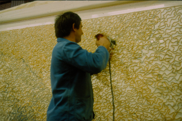 Operator, working on the back side of the canvas, is using electric needle with the combination of 3 to 5 wool colors